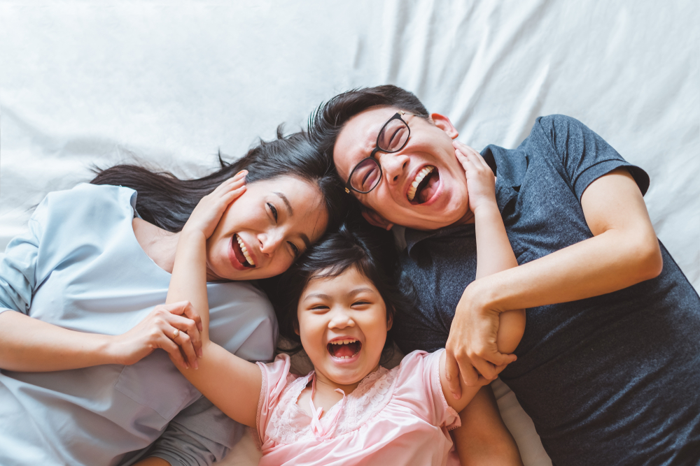 Laughing family of three lying together on a bed