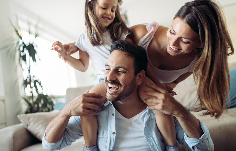 Smiling parents playing with their young daughter at home