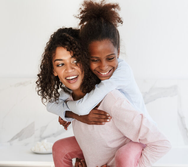 Smiling teenage girl hugging her mother from behind