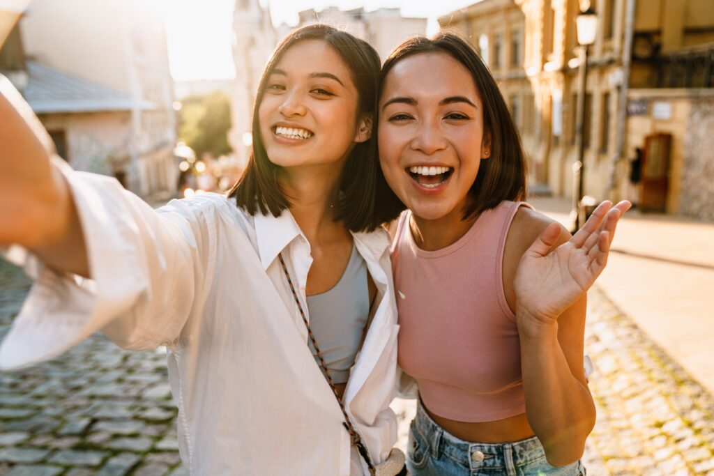 Two smiling young women taking a selfie on a city street
